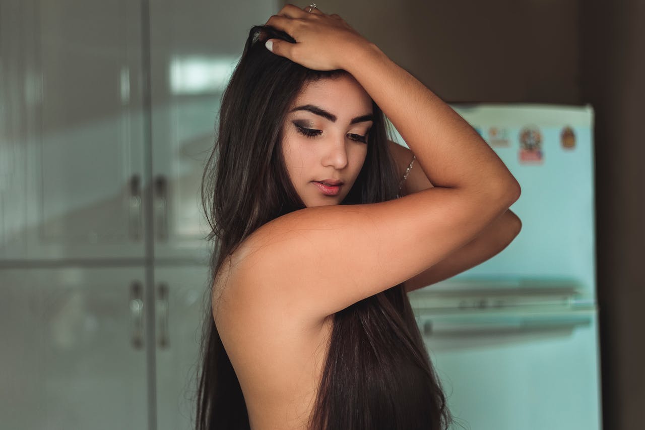 Elegant portrait of a young woman with long hair and makeup posing indoors. Modern and stylish photography.